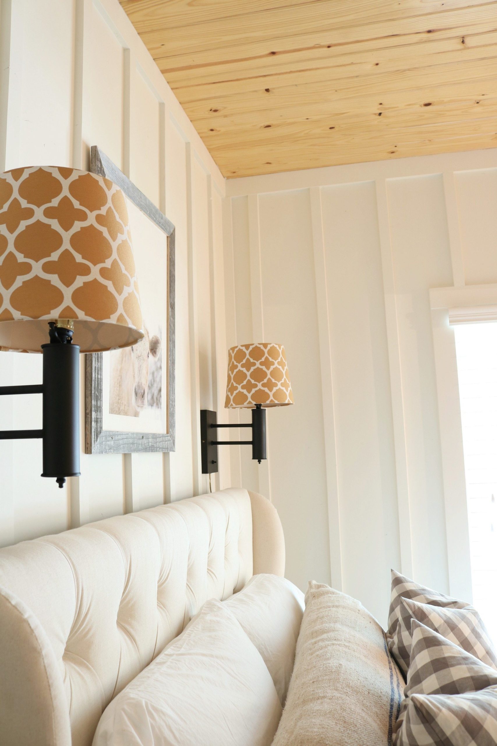 Light and bright farmhouse bedroom with flat black lights above the bed